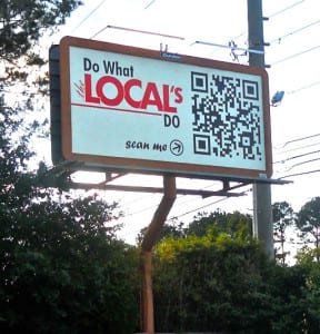 Groot reclamebord langs een weg, waarop een advertentie met QR-code staat.