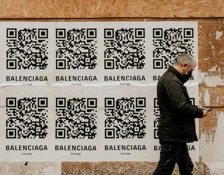 8 posters met QR codesgeplakt op een muur langs een straat als reclame voor Balenciaga.