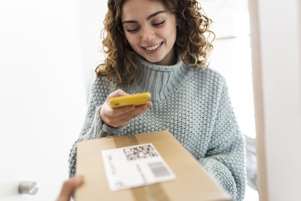 Vrouw scant een QR-code op een pakketje met haar telefoon.